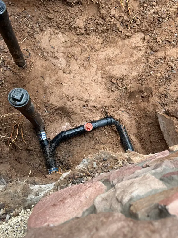 Close-up of newly installed black ABS sewer line and cleanout piping in an open trench at a casita build